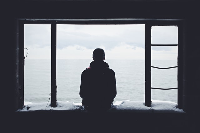 Upset man staring out the window looking to sea